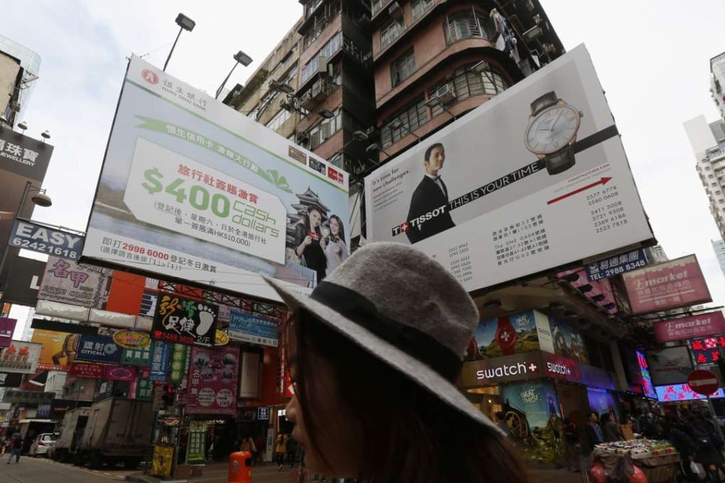A woman crossing a street lined with stores in Mong Kok in Kowloon. Photo: Reuters