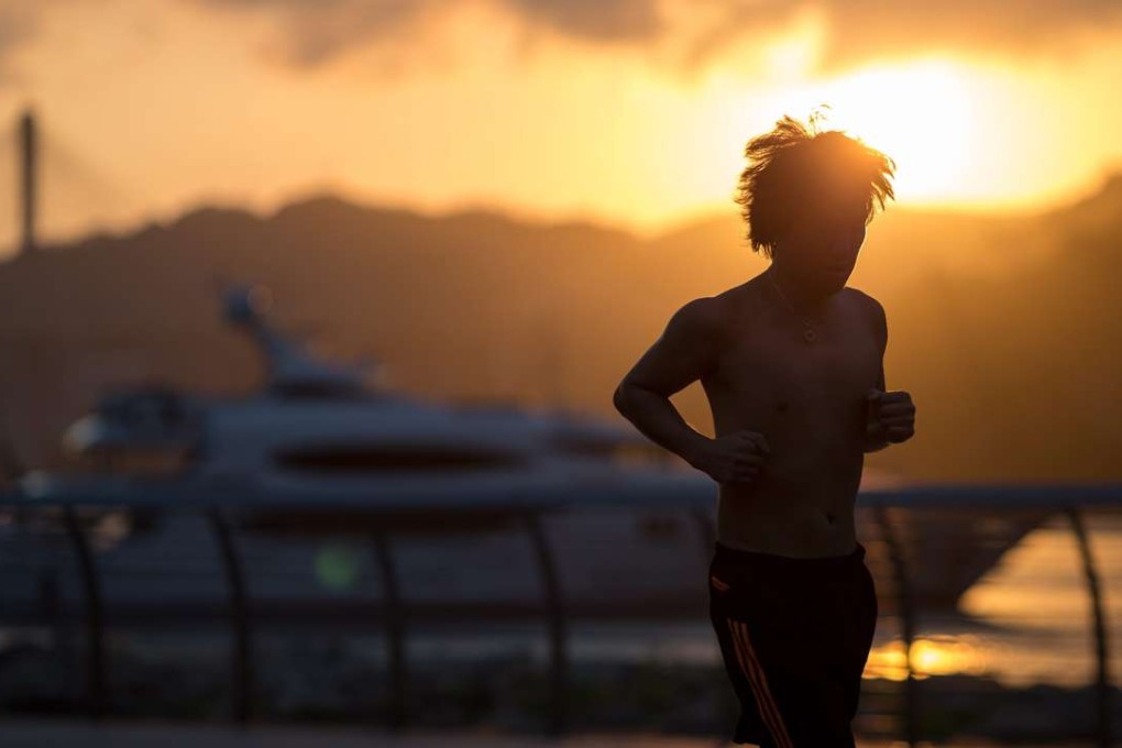 A man jogs at sunset on the waterfront in Tsing Yi. The government must take to the Town Planning Board its own proposals for several satellite towns in the New Territories. Photo: EPA