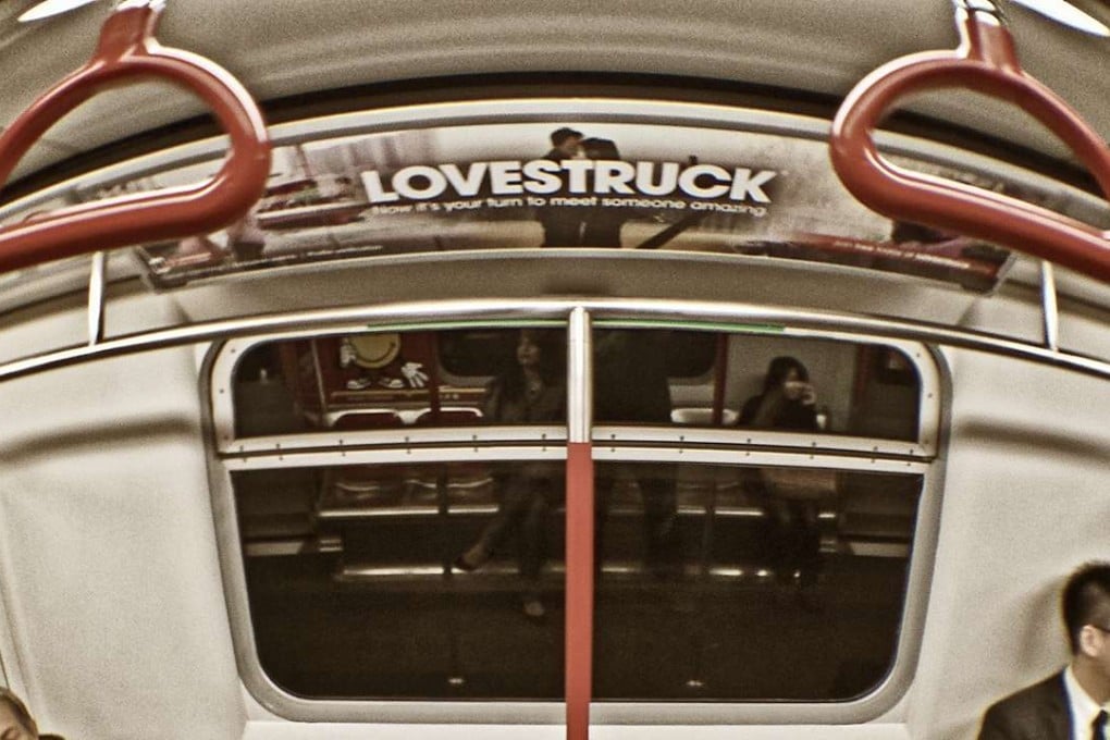 Two passengers on the MTR, with a sign "lovestruck" placed above, in Hong Kong. Photo: Sai Ying Pun. ]