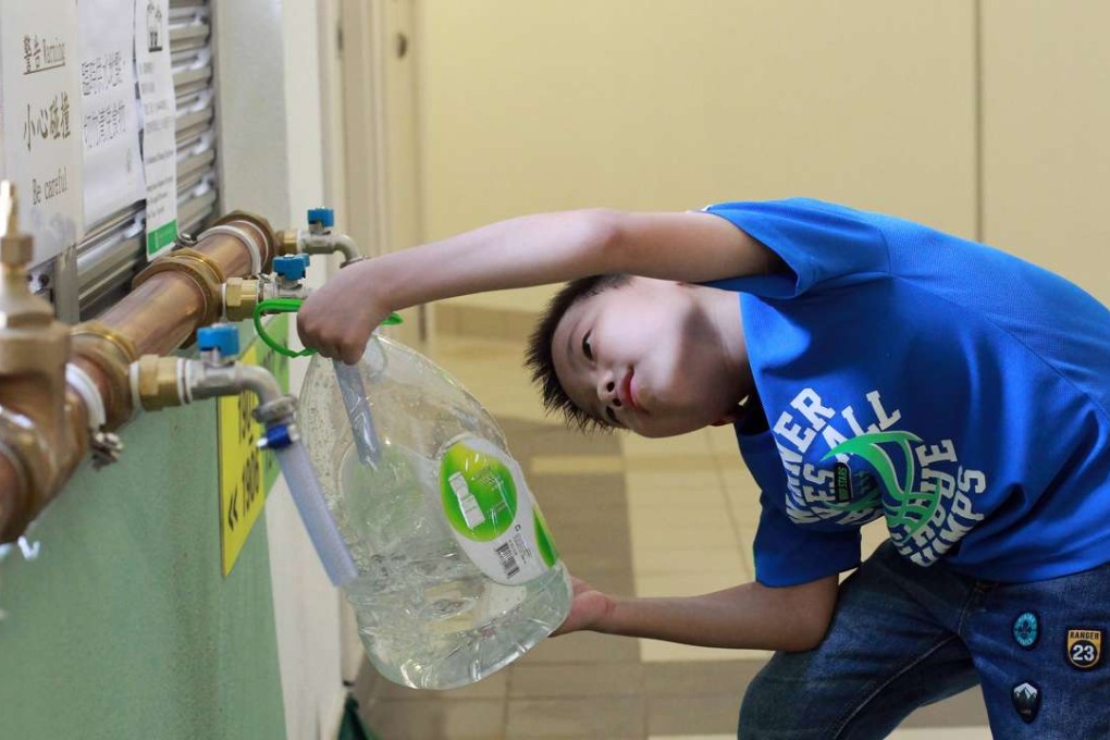 Edmond Ng Yat-long, eight, fetches water from temporary pipes in Kai Ching Estate. Photo: SCMP Pictures