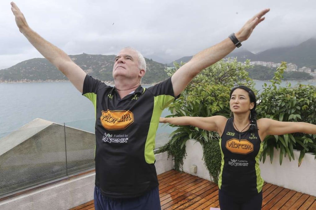 Anthony Root and personal trainer Jinhwa Kim raise their arms in a sun salutation on Root’s rooftop. Photos: Dickson Lee