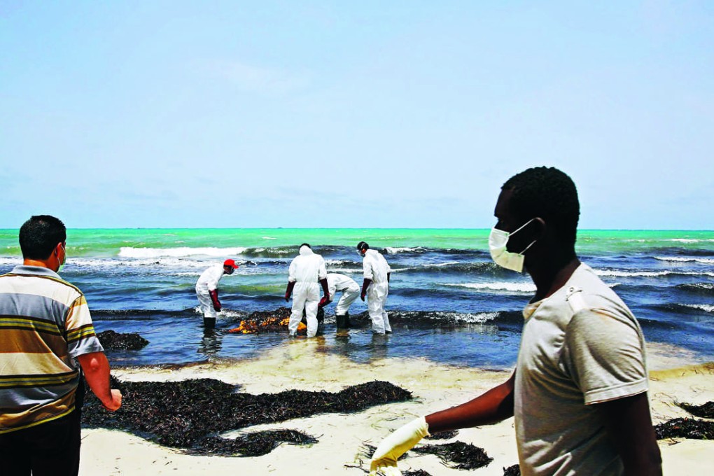 Libyan Red Crescent personnel retrieve the body of a migrant that washed up in the port city of Zuwarah on Thursday. Photo: AFP