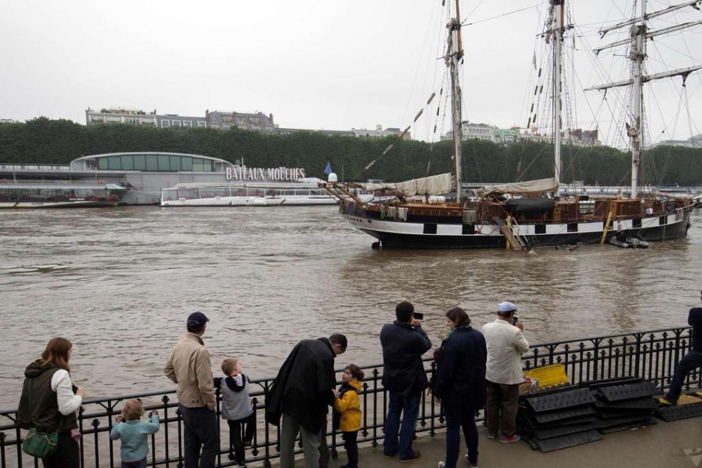 People look at a three-master ship as it sails on the rain-swollen River Seine on Sunday in Paris. Photo: AFP