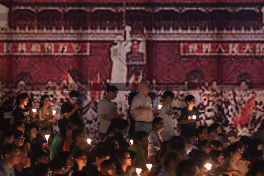 Participants hold candles during a vigil in Victoria Park, Hong Kong, for the 27th anniversary of the Tiananmen Square crackdown, in front of a large banner showing the Beijing demonstrations. Many of those who attended nurse hopes for a democratic China. Photo: AFP