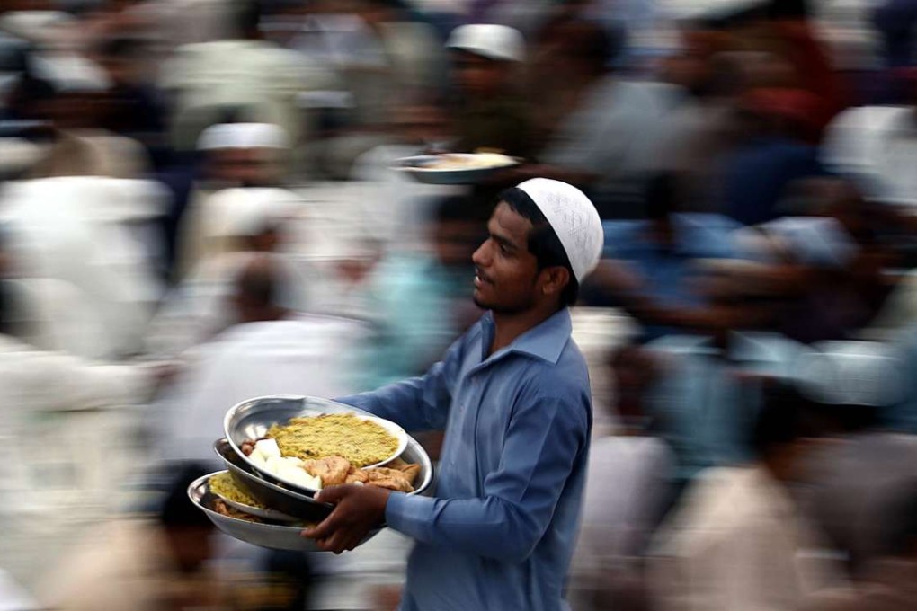 A man serves food for Iftar, breaking the fast, at a mosque during the first day of Ramadan in Karachi, Pakistan. Photo: EPA