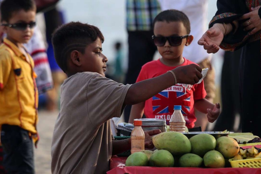 A boy sells mangoes at a beach in Mumbai, India. The Indian government has passed legislation to prohibit children between 14 and 18 years old from engaging in hazardous occupations. However, children under 14 are allowed to work in non-hazardous family enterprises and entertainment occupations. Photo: EPA