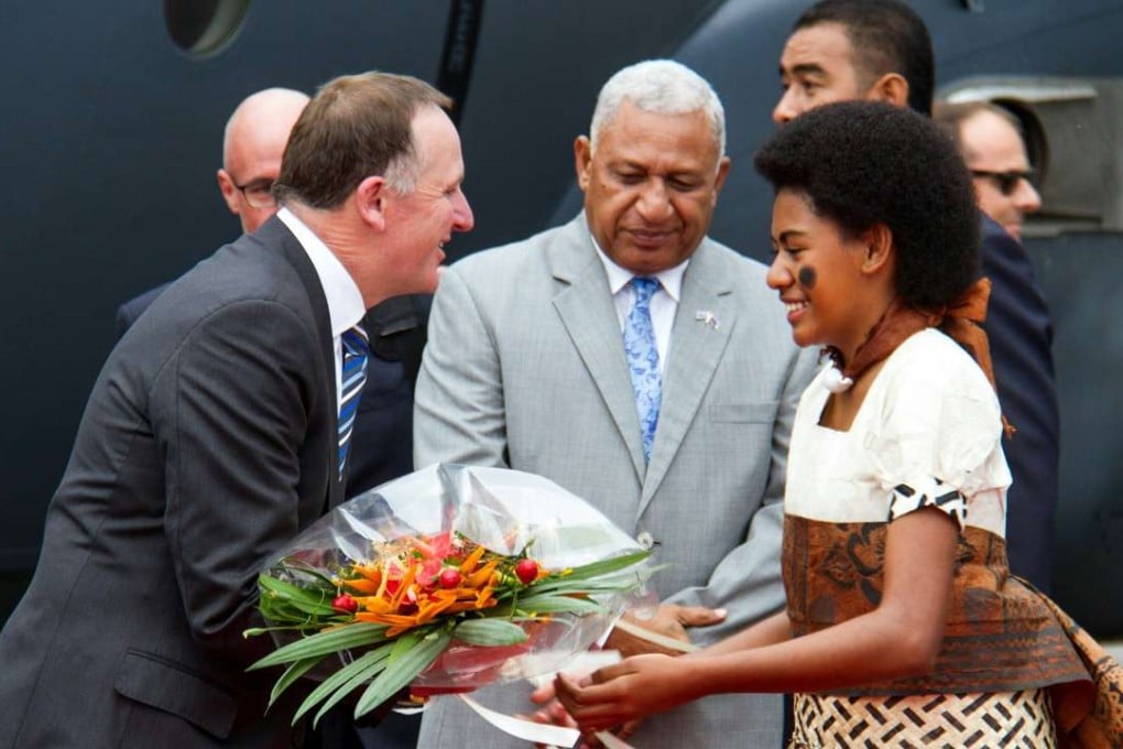 New Zealand's Prime Minister John Key (left) receives a bouquet as his Fiji counterpart Frank Bainimarama (centre) looks on at Suva's Nausori Airport, Fiji, on Thursday. Photo: AFP
