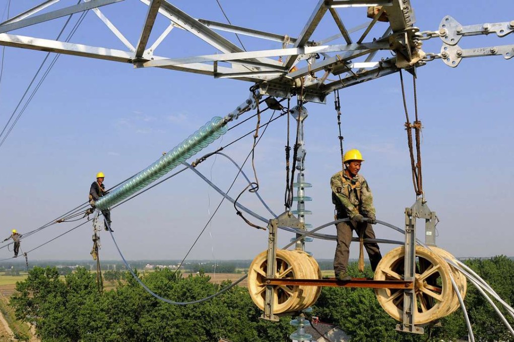 Workers install wires on an electricity pylon in Chuzhou, Anhui province on May 25, 2015. Photo: Reuters