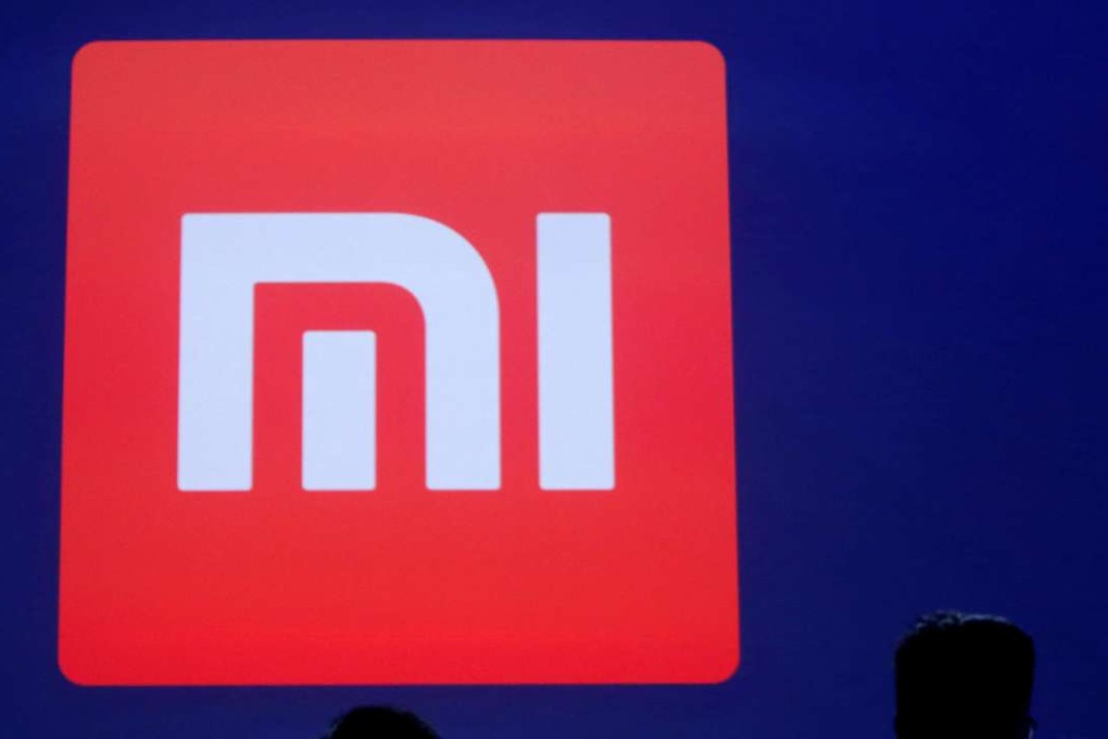 Attendants are silhouetted in front of Xiaomi's logo at a venue for the launch ceremony of the Mi Max in Beijing on May 10, 2016. Photo: Reuters
