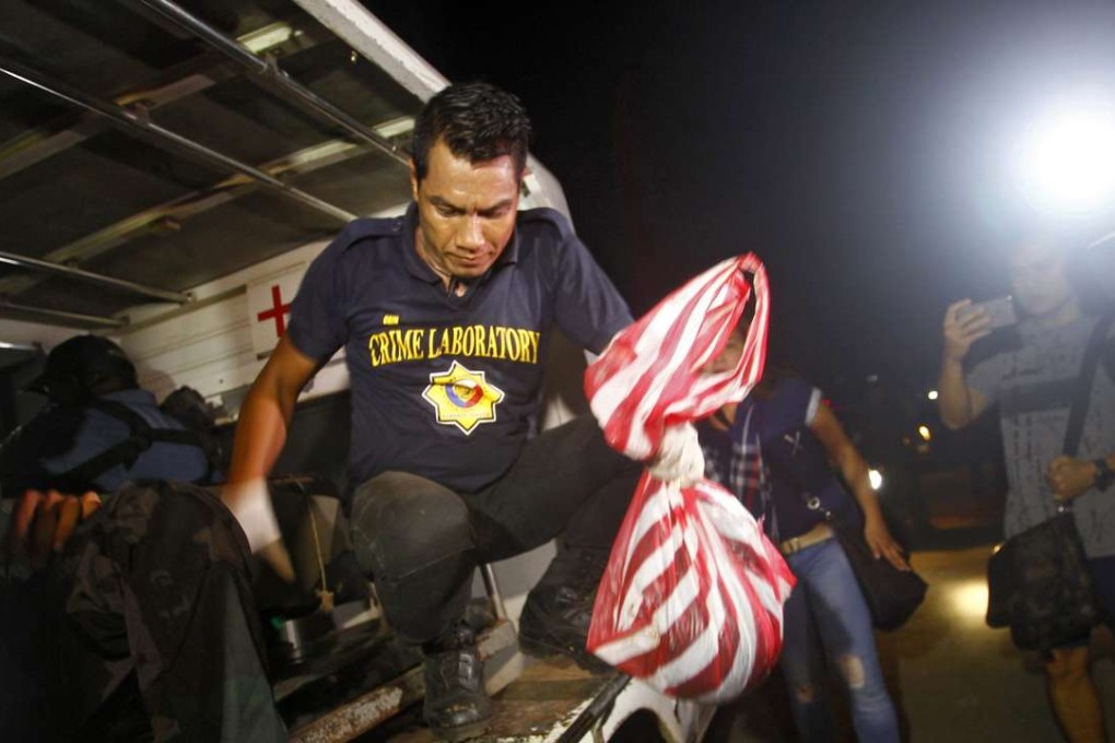 A police officer holds a plastic bag containing the recovered decapitated human head of Robert Hall in the town of Jolo, Sulu island. Photo: EPA