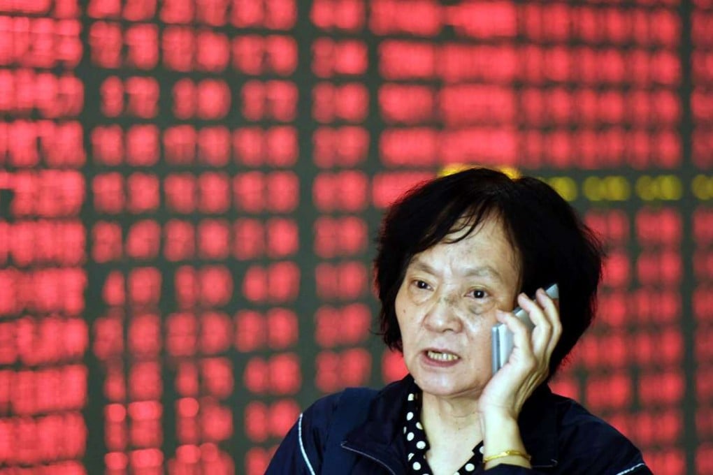 A Chinese investor makes a phone call in front of a screen showing stock market movements at a securities firm in Hangzhou, eastern China's Zhejiang province. Photo: AFP