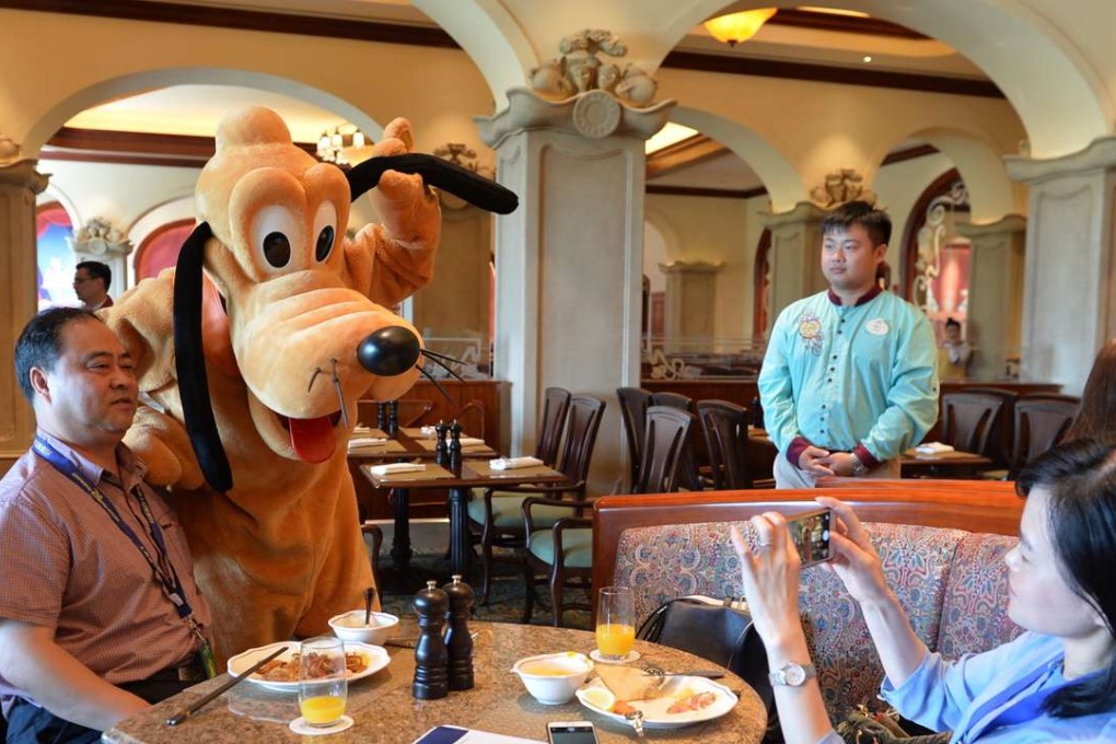A visitor poses for photos with Pluto at the Shanghai Disneyland Hotel earlier this month. The new Disney resort, the sixth in the world, officially opens on June 16. Photo: Liu Xiaojing, Xinhua