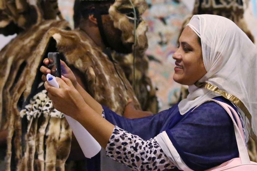 This woman from Bangladesh takes a picture at the ‘We Are Here’ exhibition on refugees. Photo: Nora Tam