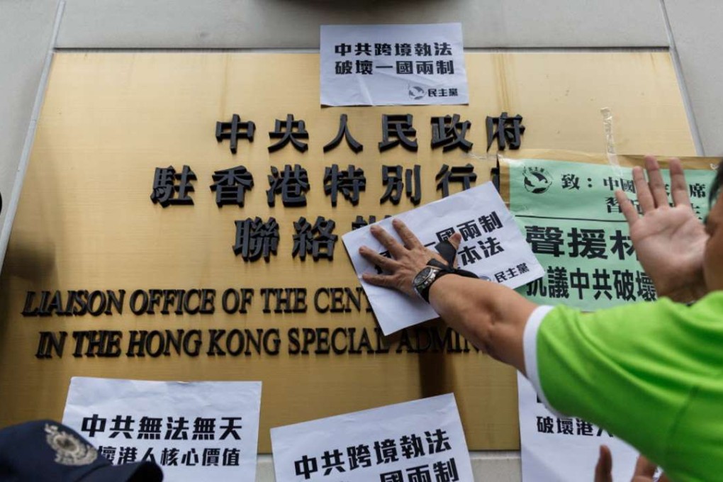 A Democratic Party member places handbills that translate as "Hong Kongers support Lam Wing-Kee" and "Chinese Communist enforcing the law across border destroy the One Country-Two Systems" upon signage for the Chinese Liaison Office during a proteston Friday. Photo: AFP
