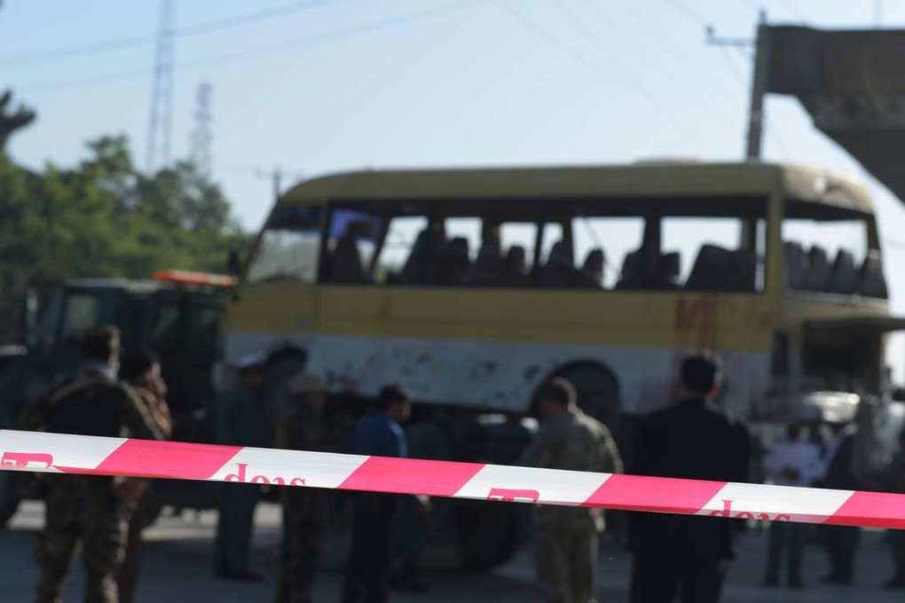 Afghan policemen look at the site of a suicide attack to have hit a minibus carrying foreign security guards. Photo: AFP
