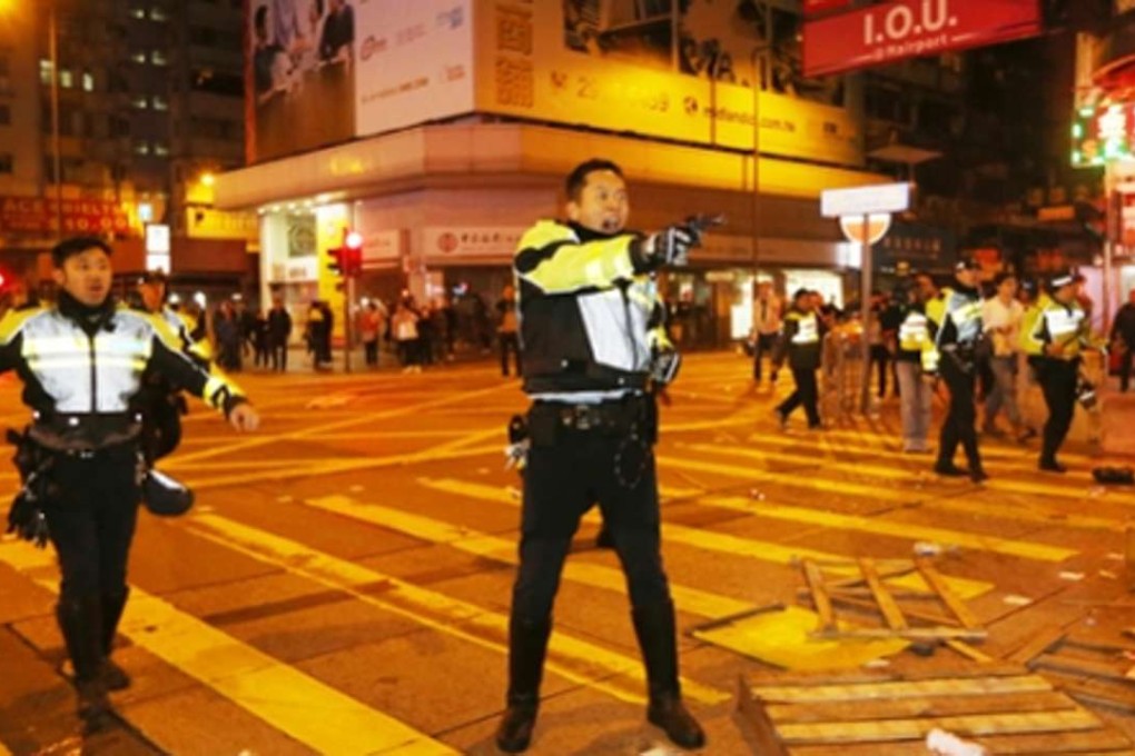 A policeman draws his gun during the Mong Kok riot. Photo: SCMP Pictures