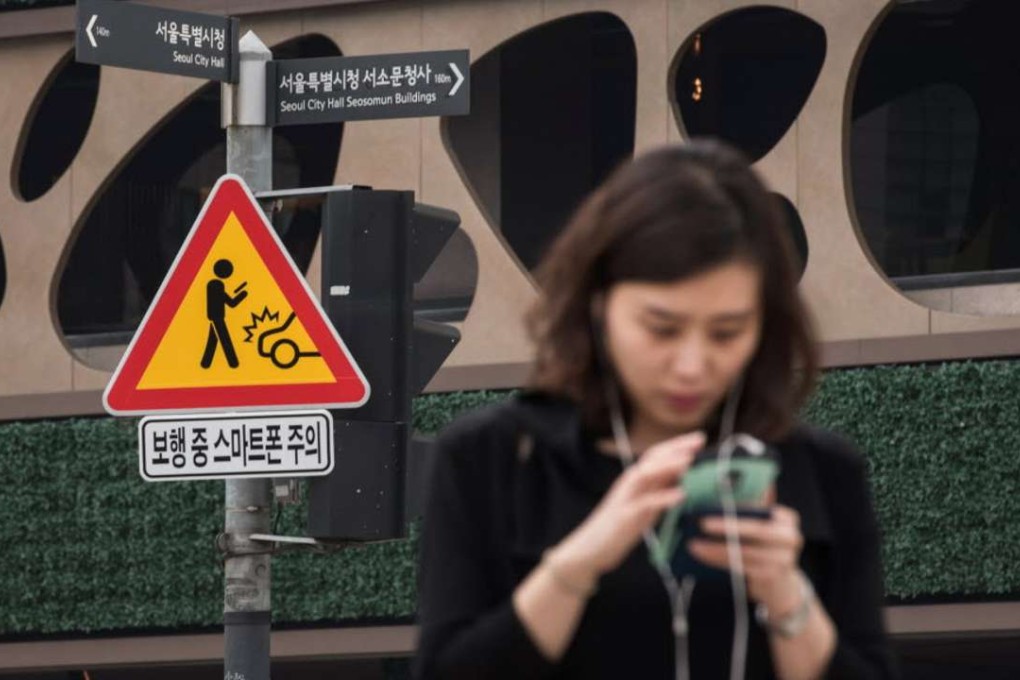 A sign advising pedestrians of the dangers of using smartphones while walking is displayed at an intersection in Seoul. Photo: AFP