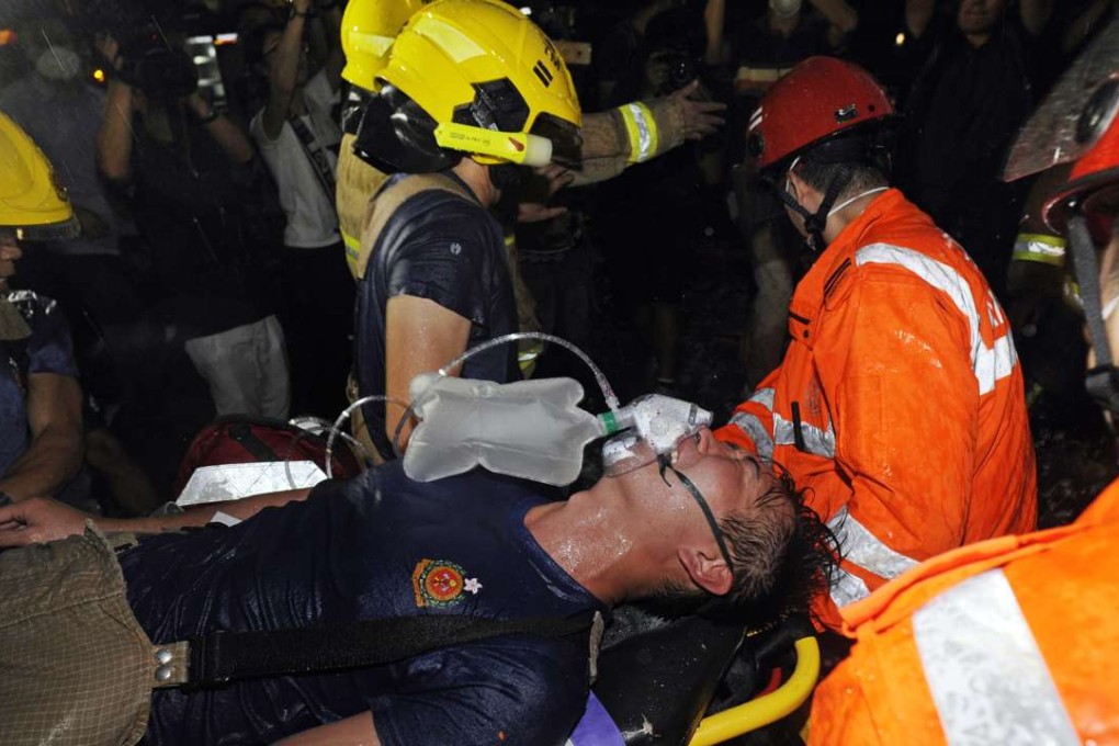 An injured fireman battling the blaze inside the industrial building is rushed into an ambulance yesterday. Photo: SCMP Pictures