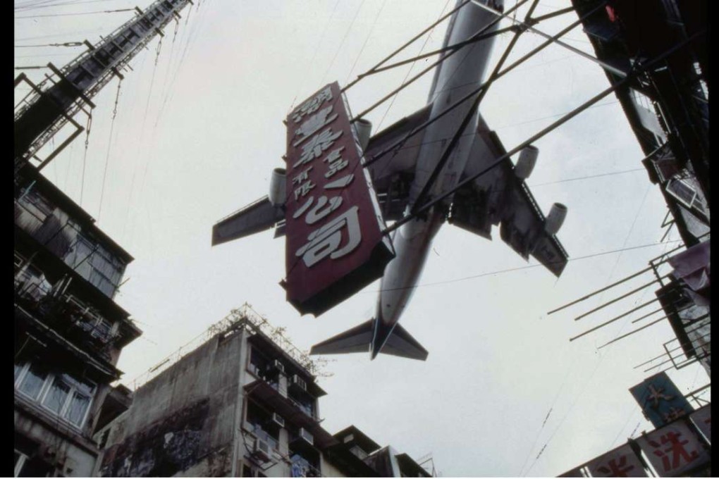 A classic shot of a rooftop-skimming plane approaching Kai Tak airport in the Retro Kowloon exhibition by Henry Chung.