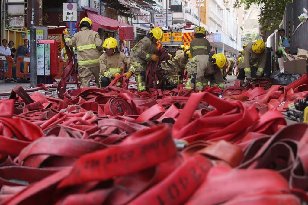 Firemen pick up their equipment after 5 days of 4th alarm fire in Ngau Tau Kok industrial building continues. Photo: Sam Tsang