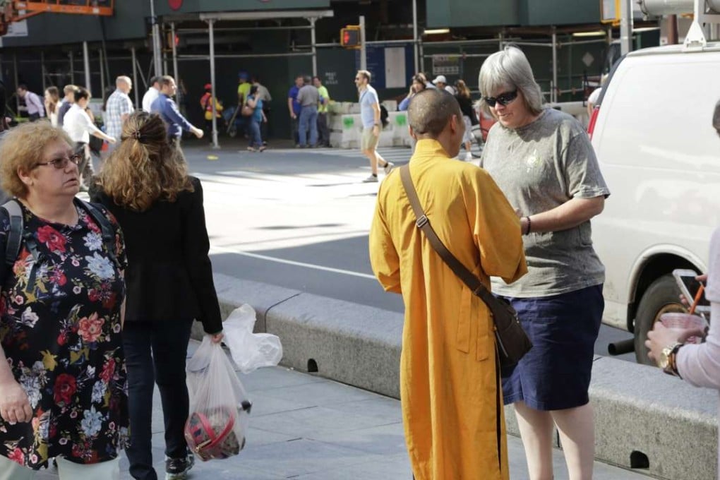 A man wearing the orange robe of a Buddhist monk talks with a woman in New York's Times Square. The Buddhist Council of New York says such men are “fake monks” who are not affiliated with any known temple and are just looking to make a quick buck. Photo: AP