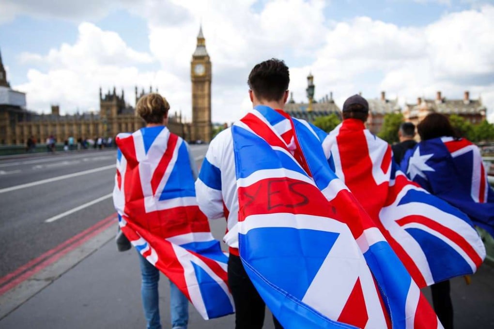 People walk over Westminster Bridge wrapped in Union flags, towards the Big Ben and the Houses of Parliament in central London. Photo: AFP