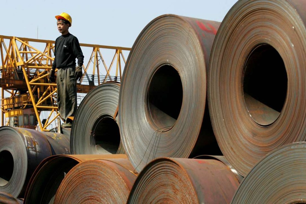 A worker stands on a stack of rolled steel, shipped from the Baosteel factory in Shanghai, on a dock at Guangzhou, Guangdong province. Photo: Greg Baker, AP
