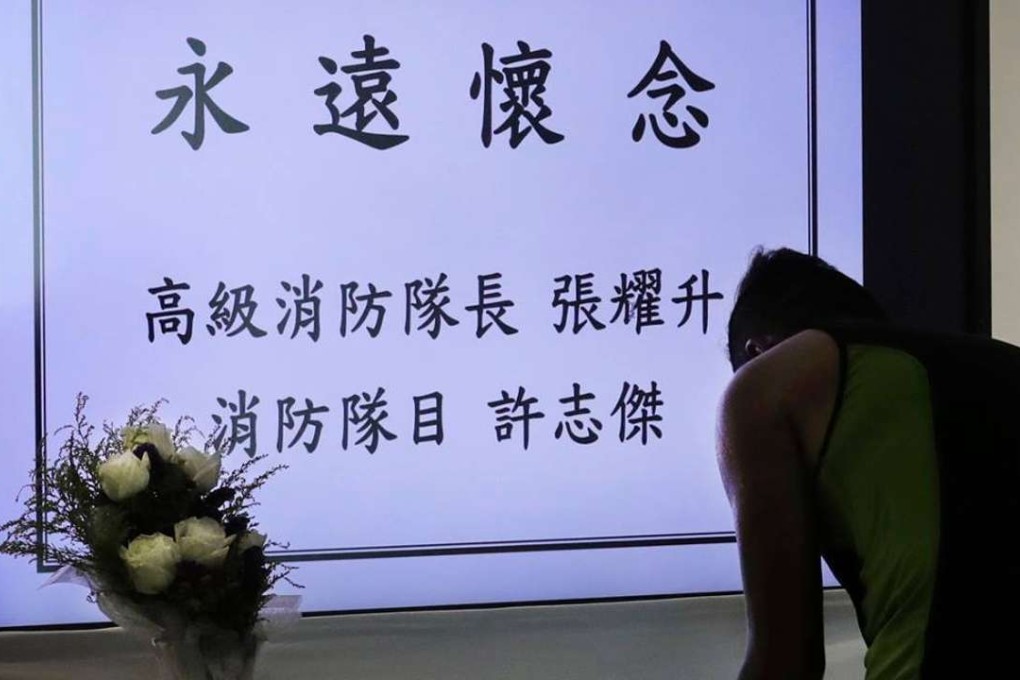 A fireman signs a book of condolence for two firefighters at the Fire and Ambulance Services Academy. Photo: Edward Wong