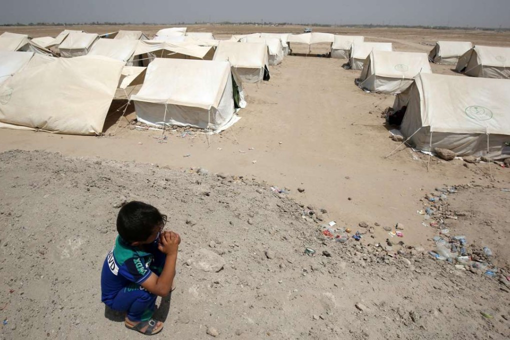 An Iraqi boy from Fallujah squats nearby tents at a newly opened camp in the desert. Photo: AFP