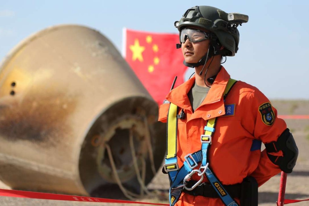 A member of the Chinese search team stands guard beside the re-entry module in the Badain Jaran Desert in Inner Mongolia on Sunday. Photo: Xinhua