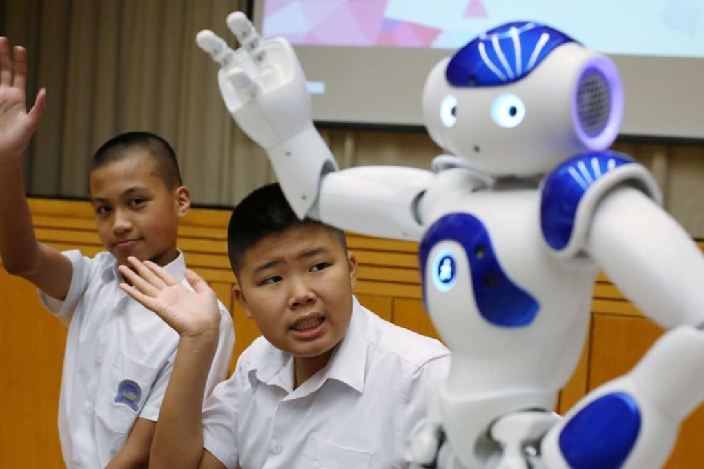 Lam Wai-lok (left) and Keung Hei-man with a ‘’social robot’’ that aims to improve the essential hand gestures of autistic children. Photo: Nora Tam