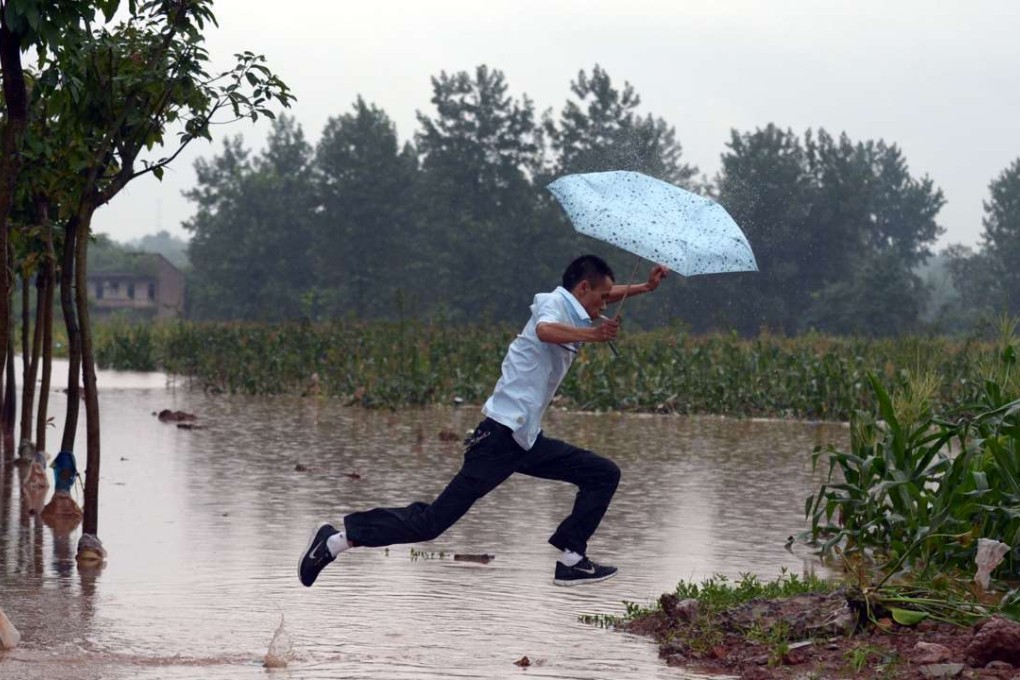 This file photo shows a man jumping across a flooded path on the outskirts of Chongqing. Officials say flood control efforts in central and eastern china have reached a ‘critical’ stage. Photo: AFP