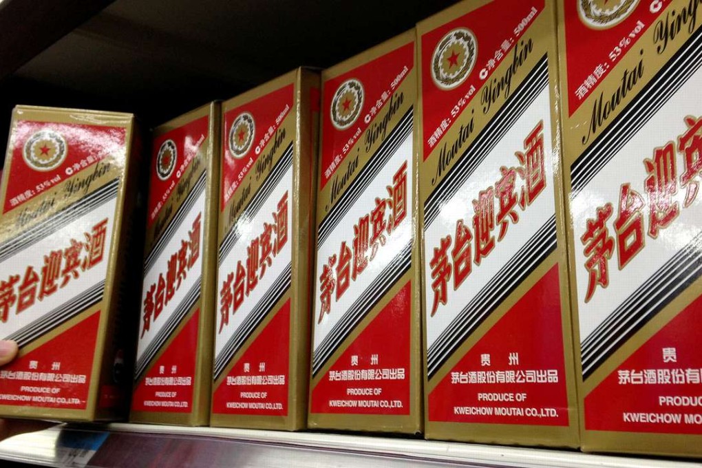 A man takes a bottle of mao-tai liquor from a supermarket shelf in Beijing. Photo: Xinhua
