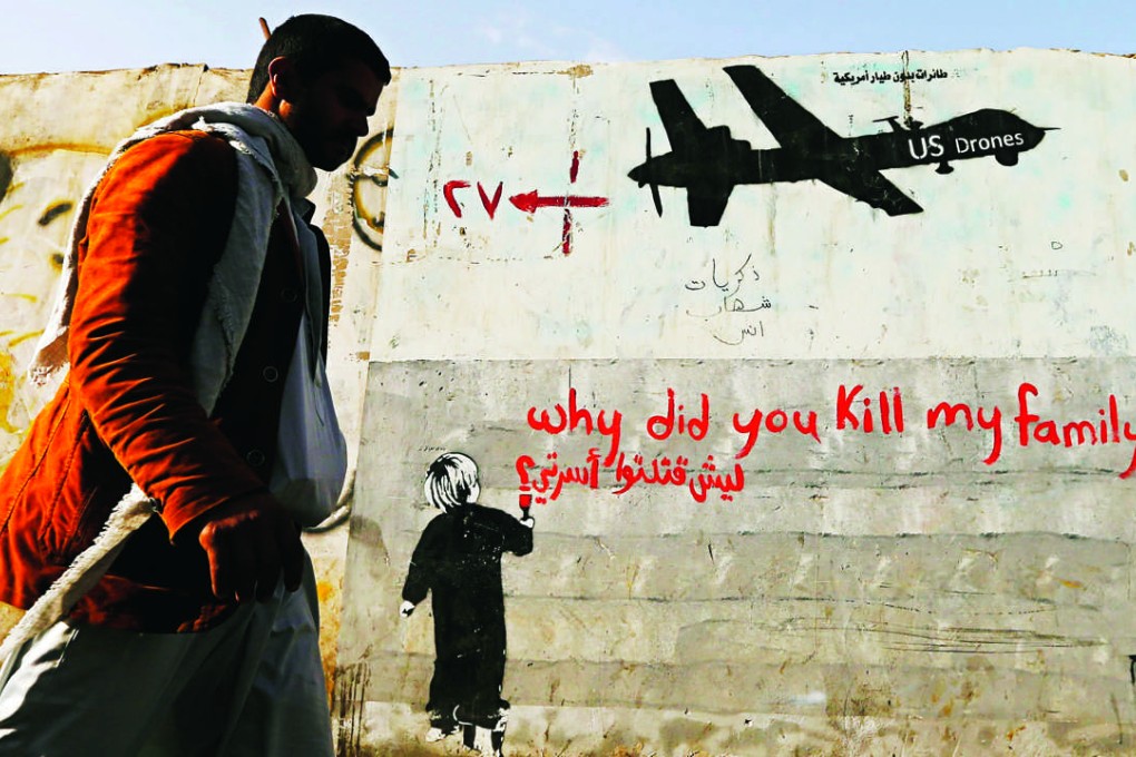 A man walks past graffiti denouncing strikes by US drones in Yemen, painted on a wall in Sanaa. Photo: Reuters