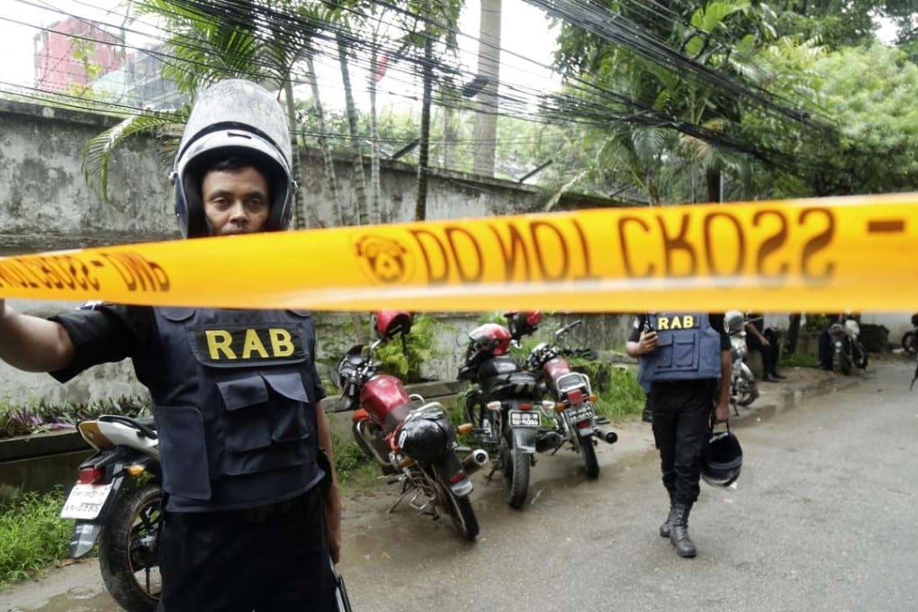 Members of the Rapid Action Battalion behind tape to stop media and others in the streets close to the Holey Artisan Bakery. Photo: EPA
