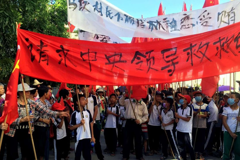 Villagers carry banners reading “Plead to the central government to help Wukan” and “Wukan villagers don't believe Lin Zuluan took bribes” during a protest in Wukan on June 22. Photo: Reuters