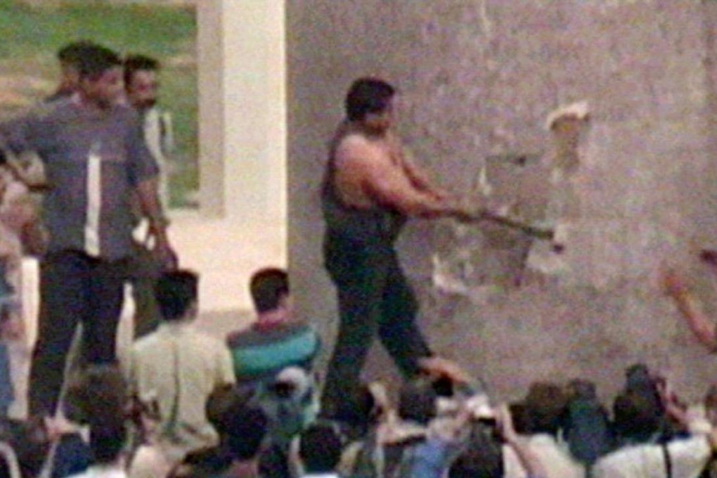 Kadhim Sharif al-Jabouri uses a sledgehammer to attack the base of a statue of Saddam Hussein in Baghdad on April 9, 2003. Photo: Reuters TV