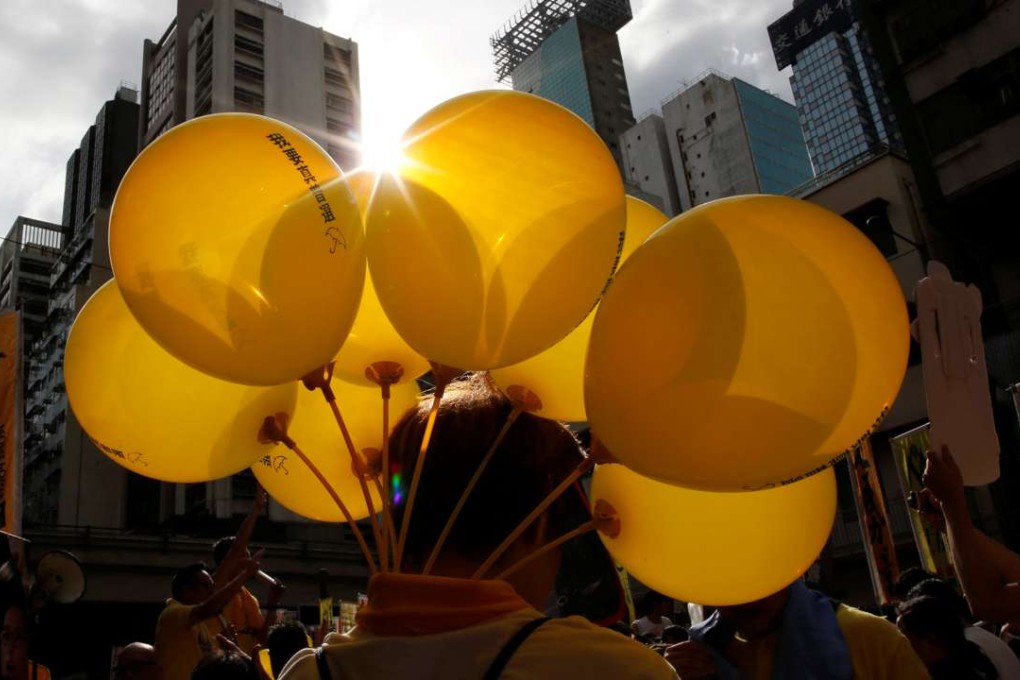 A protester carries yellow balloons featuring umbrellas, the symbol of the Occupy Central movement, during a protest march on July 1 this year. Photo: Reuters