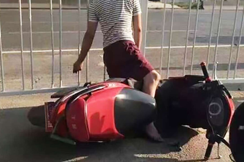 The body of a man is suspended by his neck, which is trapped between the bars of a road fence. Photo: SCMP Pictures