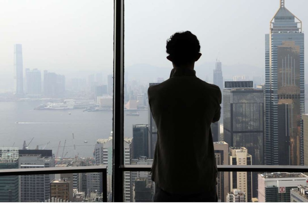 A man looks out at a hazy harbour from a high-rise office in Wan Chai. Photo: Felix Wong