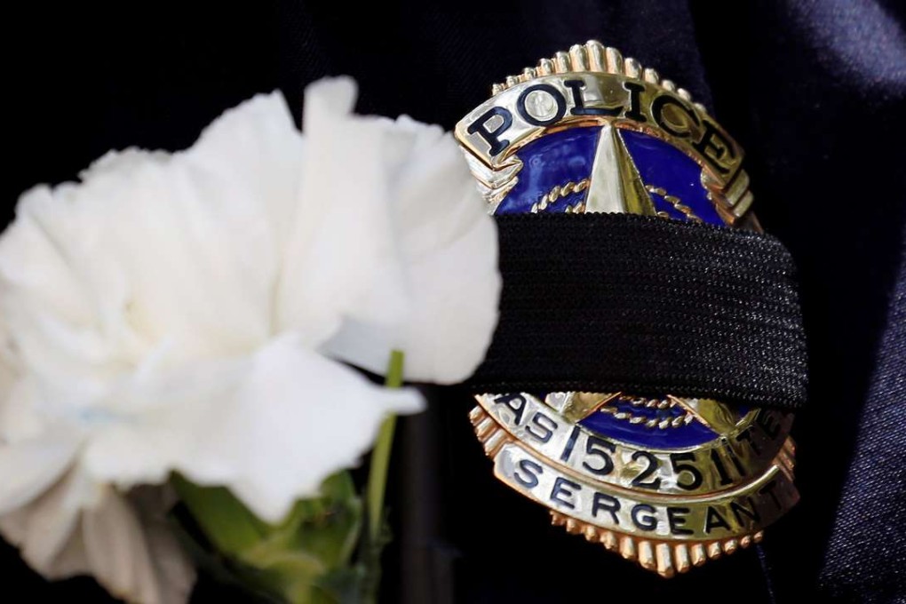 A Dallas police sergeant wears a mourning band and flower on his badge during a prayer vigil, one day after a lone gunman ambushed and killed five police officers at a protest decrying police shootings of black men, in Dallas, Texas, July 8, 2016. Photo: Reuters