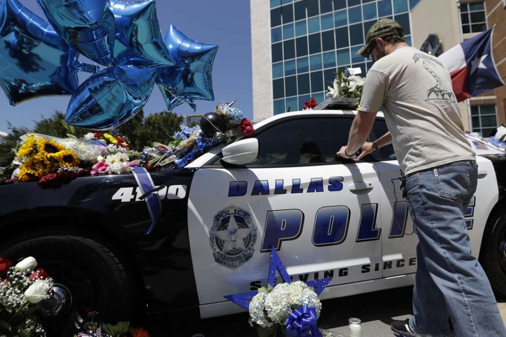 Michael O'Mahoney, a former police officer, places his patch on a make-shift memorial at the Dallas police headquarters, after five police officers are dead and several injured following a shooting in downtown Dallas. Photo: AP