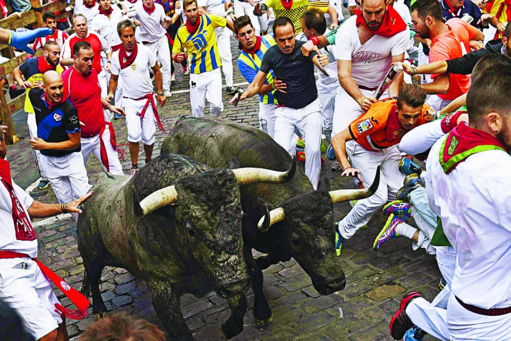 Bulls run past revellers during the third bull run of the Festival of San Fermin in Pamplona. Photo: EPA