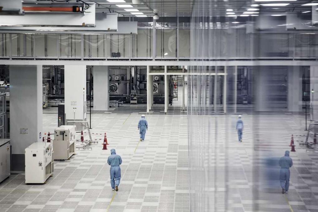 Employees wearing protective suits walk past machinery on the fully automated assembly line at a BOE Technology factory in Chongqing. Photo: Bloomberg