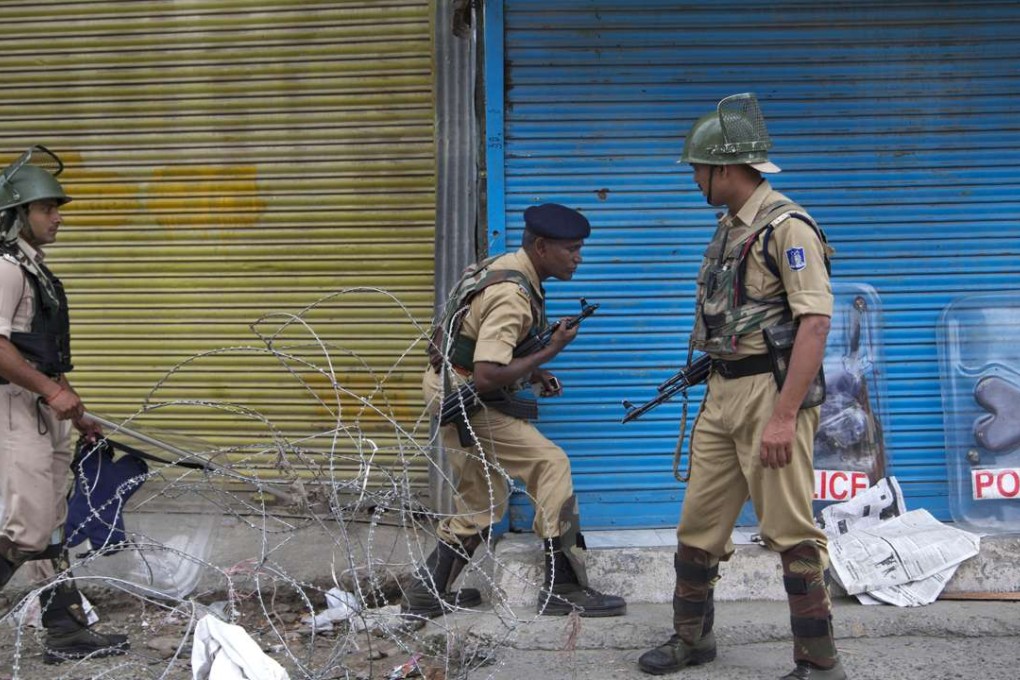 Indian paramilitary soldier cross barbed wire set up as road blockade at a temporary checkpoint during curfew in Srinagar. Photo: AP