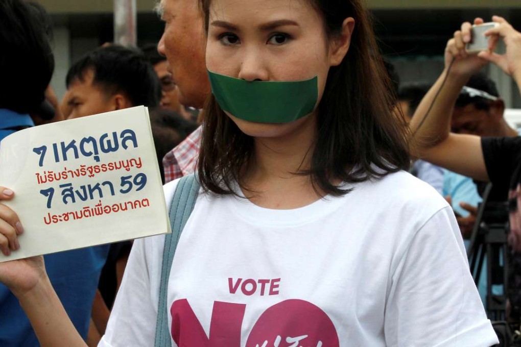 An activist against the junta-backed constitution seals her mouth with duct tape and holds a placard reading "7 Reasons To Not Accept Constitution". Photo: Reuters