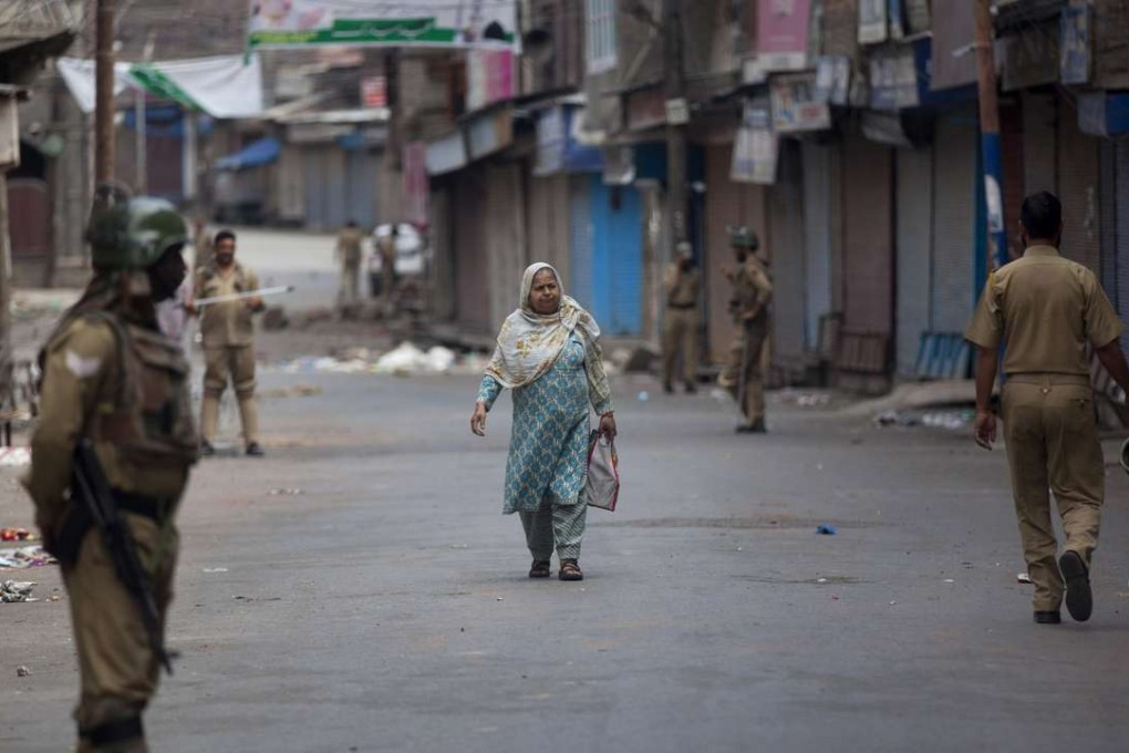 A Kashmiri woman walks past Indian paramilitary soldiers standing guard during curfew in Srinagar. Photo: AP