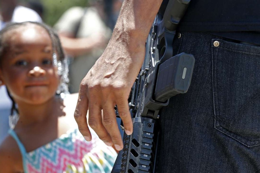 A child stands nearby as Jasiri Basel, an open carry advocate talks to reporters in front of the Triple S Food Mart in Baton Rouge, Louisiana, on Thursday. Photo: AP