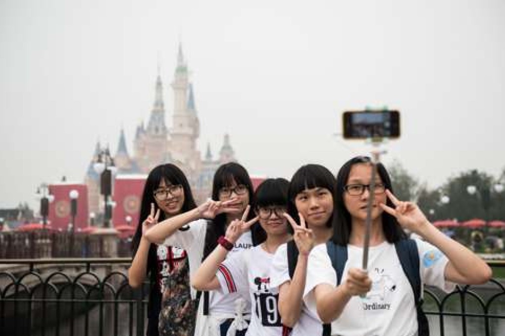 Visitors take a selfie after the opening ceremony of the Shanghai Disney Resort in Shanghai on June 16, 2016. Entertainment giant Disney opened a massive theme park in Shanghai on June 16, hoping to win over communist-ruled China's growing middle class with the ultimate US cultural export. / AFP PHOTO / JOHANNES EISELE