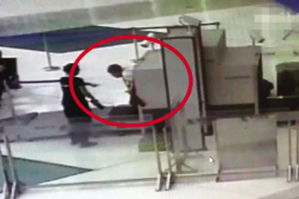 The man crawls out of Yujiabao Railway Station’s security scanning machine on Sunday. Photo: SCMP Pictures